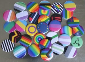 a pile of colorful buttons with various lgbtqia+ flag patterns sitting on top of a table